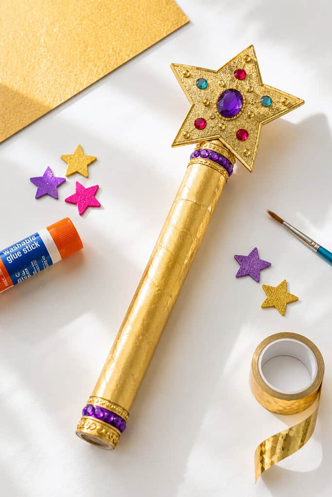 a paper towel tube or wooden dowel wrapped in metallic gold foil tape or painted gold