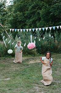 Kids having fun in a sack race during a backyard party set outdoors in summer.
