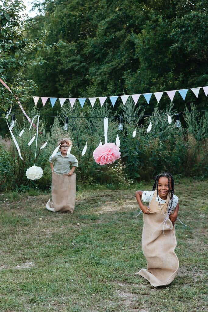 Kids having fun in a sack race during a backyard party set outdoors in summer.