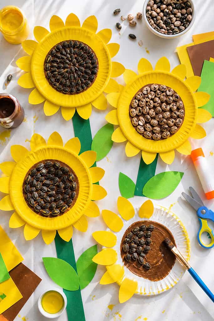 several paper plates transformed into vibrant sunflower crafts arranged across the table like a sunny little garden