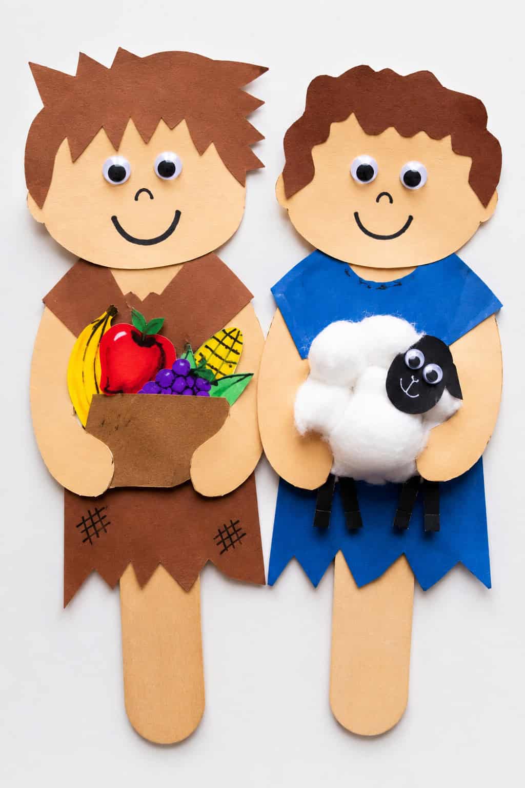 Cain and Abel using colorful construction paper cutouts, popsicle sticks, googly eyes, crayons, markers, cotton balls, and glue.