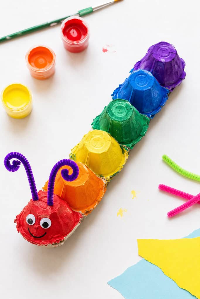 a strip of connected egg carton cups, with each individual cup painted a different bright, cheerful color such as red, orange, yellow, green, blue, and purple.