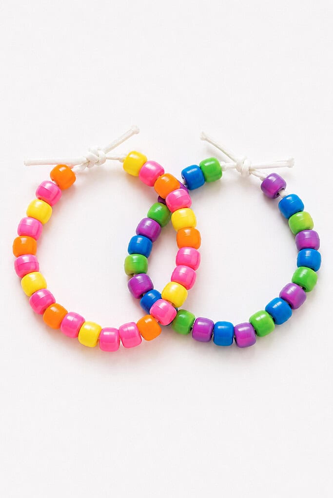 Two colorful pony bead bracelets strung on white cord and overlapping each other, one with pink, orange, and yellow beads and the other with blue, green, and purple beads