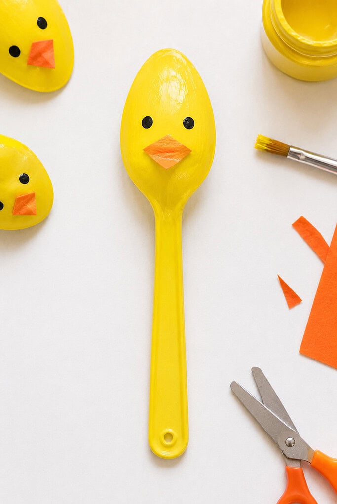a yellow-painted plastic spoon, with the spoon bowl forming the duckling's body and face.