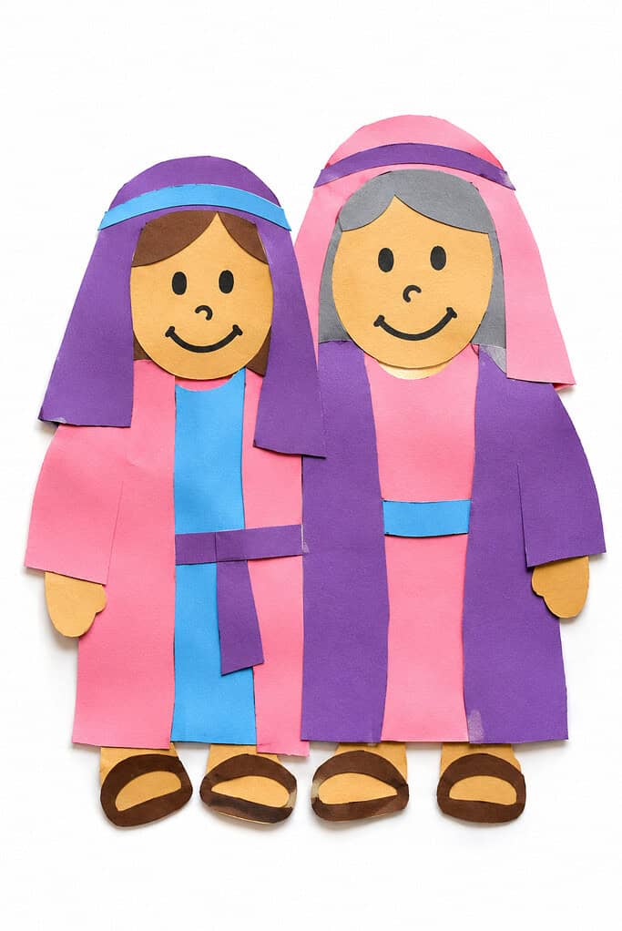 simple construction paper cutouts with visible child-made imperfections, including two smiling Bible characters (Ruth and Naomi) standing side by side