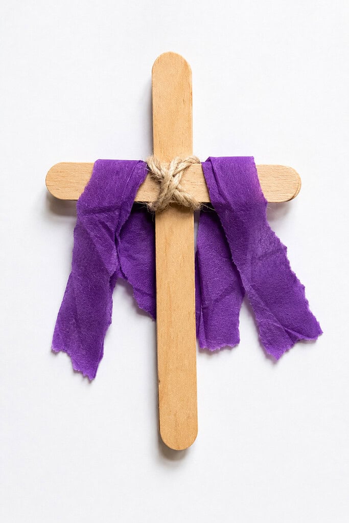 a simple cross made from two wooden craft sticks tied together with a piece of yarn.