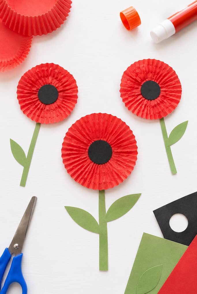 a handmade poppy flower created from a flattened red cupcake liner with a black paper circle center