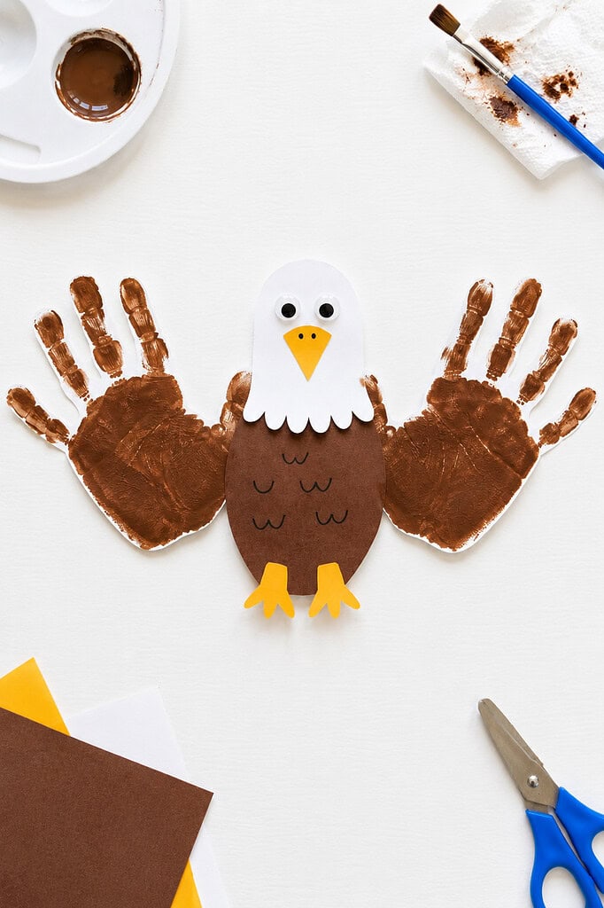 a charming bald eagle made from children's handprints, with two brown painted handprints forming the eagle's wings on either side of a handcrafted eagle body.