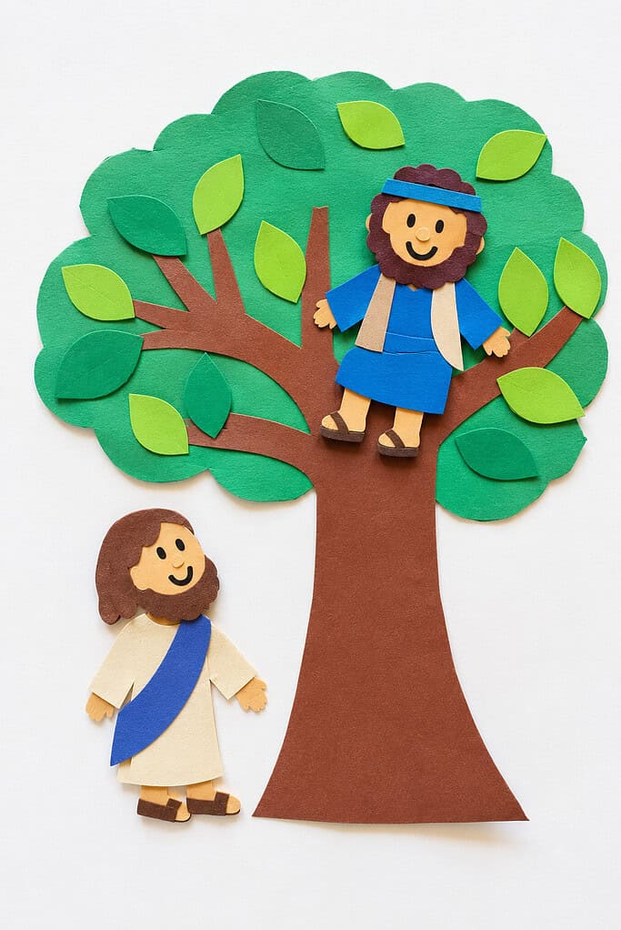 A paper craft scene showing a brown tree with a green canopy and light green paper leaves, a small smiling bearded figure in a blue robe sitting in the upper branches, and another figure with long brown hair and a blue sash standing beside the trunk