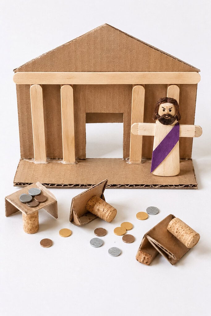 a small temple built from recycled cardboard pieces and craft sticks. In front of the temple are several tiny tables made from corks, cardboard scraps, or folded cardstock that can easily be tipped over and stood back up again.