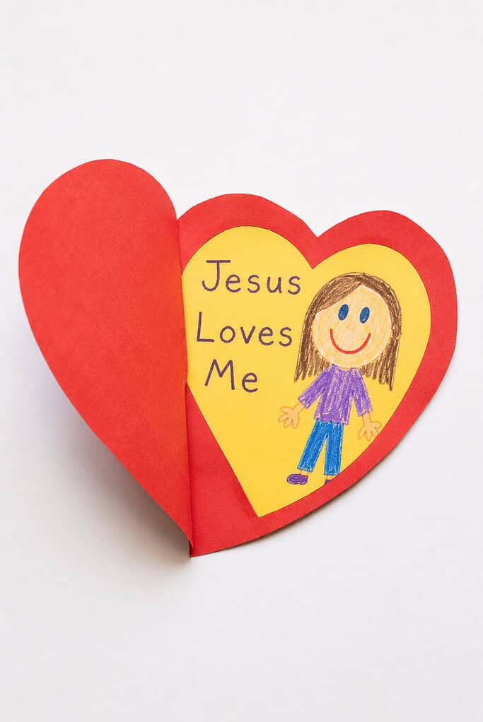 a simple child-made self-portrait inside and a small hand-lettered paper message that reads "Jesus Loves Me."