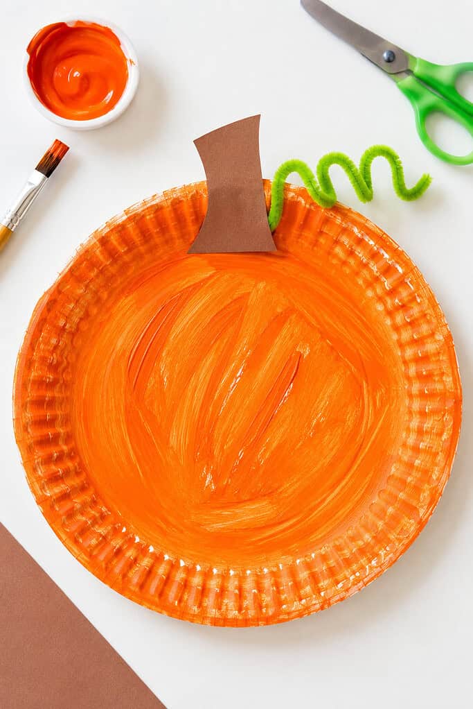 A handmade pumpkin created from a paper plate painted a vibrant orange.