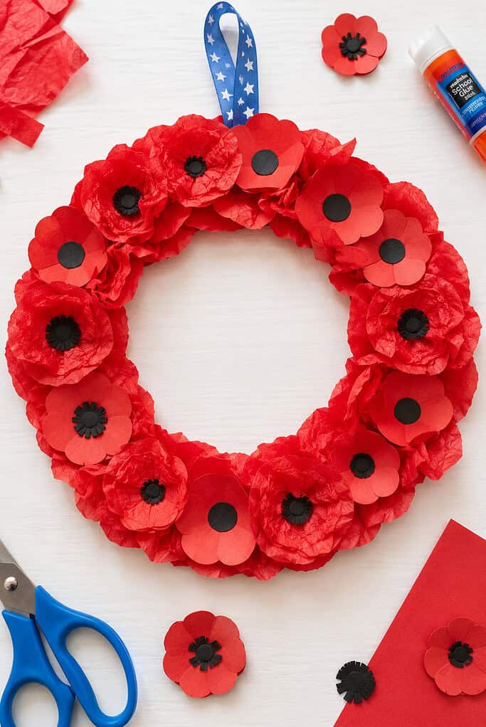 a paper plate cut into a wreath ring, completely covered with handmade red tissue-paper and construction-paper poppies