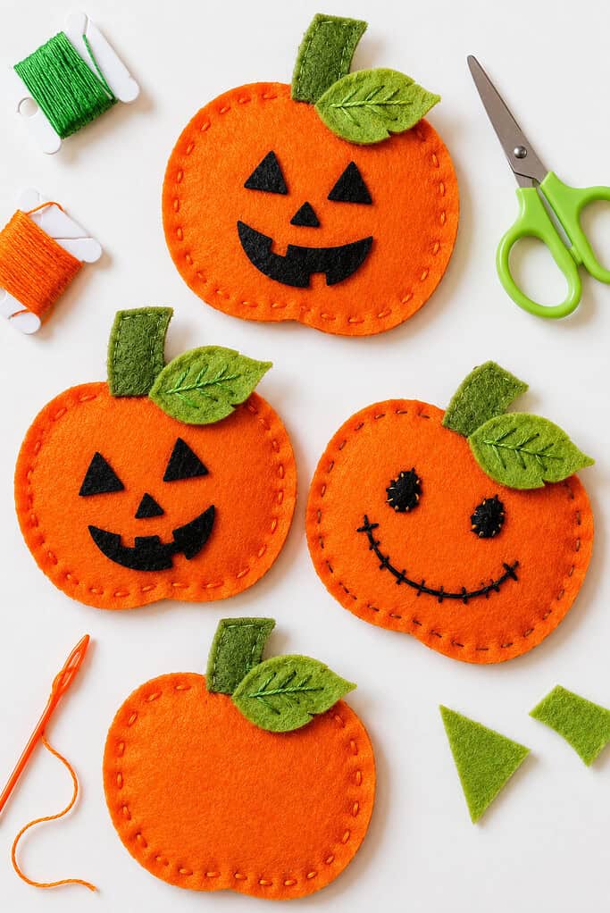 Several handmade pumpkin shapes cut from rich orange wool felt, arranged neatly as the focal point of the image.