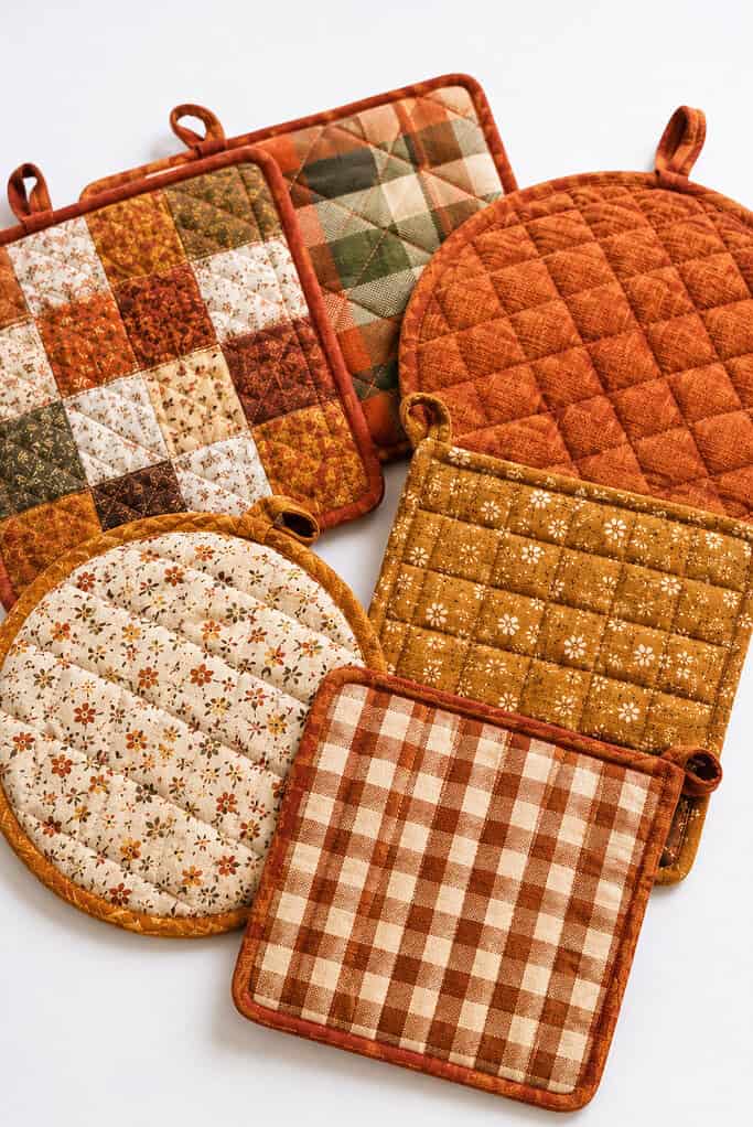 a set of finished quilted potholders and hot pads handmade from cozy autumn-inspired fabrics.