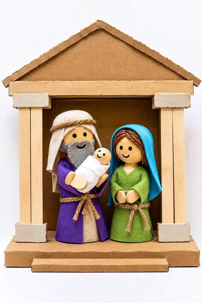 a simple temple scene made from recycled cardboard and basic craft materials. Inside the temple stand three handmade figures: Simeon, Anna, and Baby Jesus.