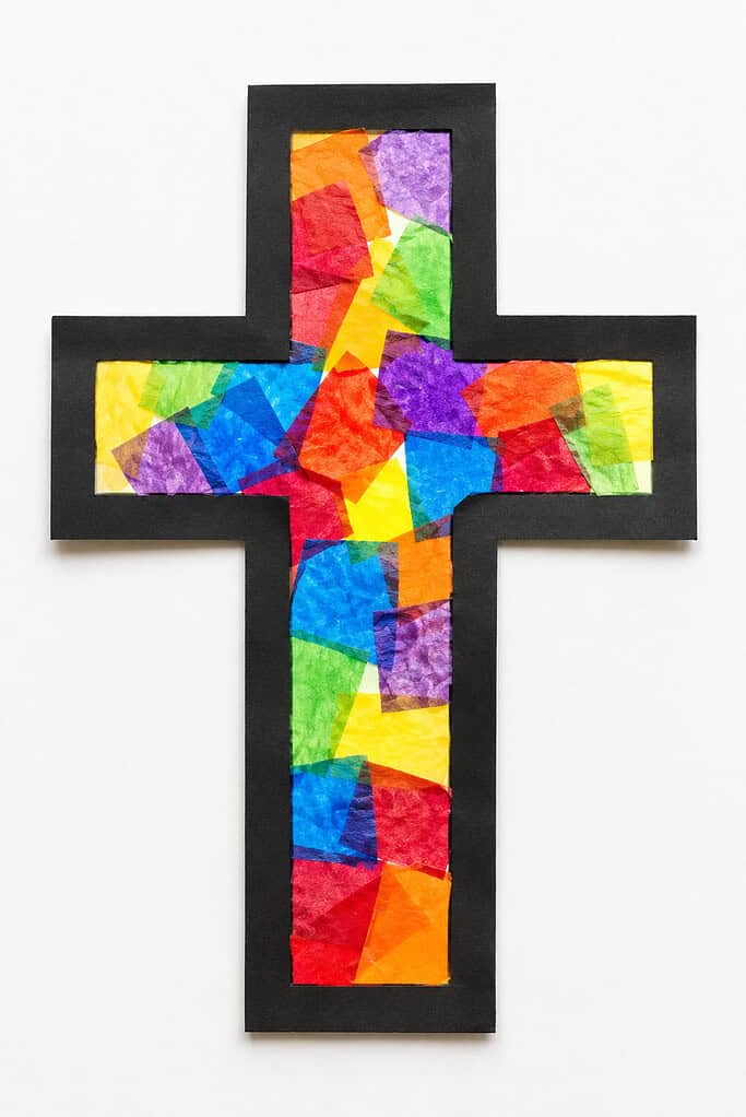 A cross cut from black cardstock filled with overlapping torn pieces of multicolored tissue paper in red, blue, yellow, green, orange, and purple