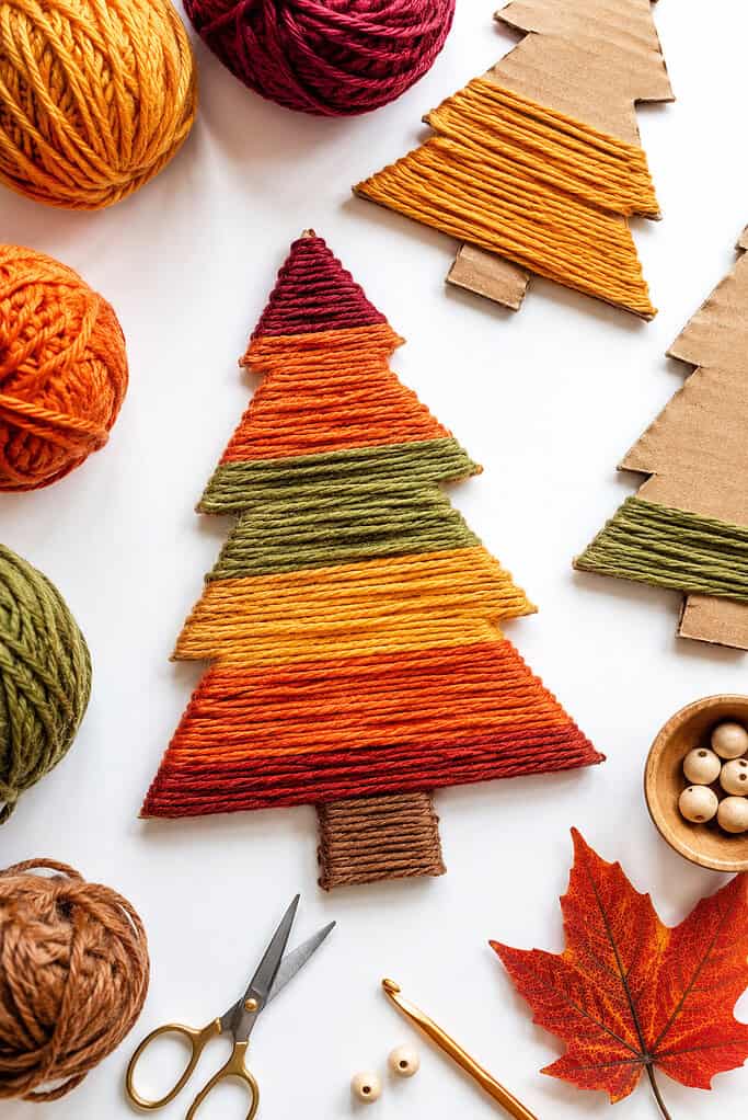 a DIY yarn-wrapped tree made from recycled cardboard, designed as a cozy fall craft for children.