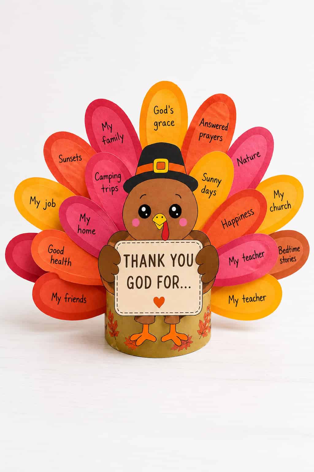 A finished paper turkey craft in a black pilgrim hat standing on a white table with orange, red, pink, and yellow paper feathers fanned out behind it