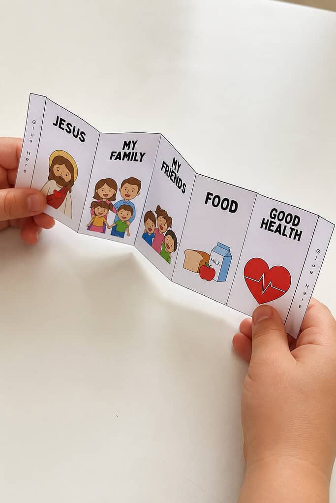 A child's hands folding a picture panel strip back and forth into an accordion on a white table