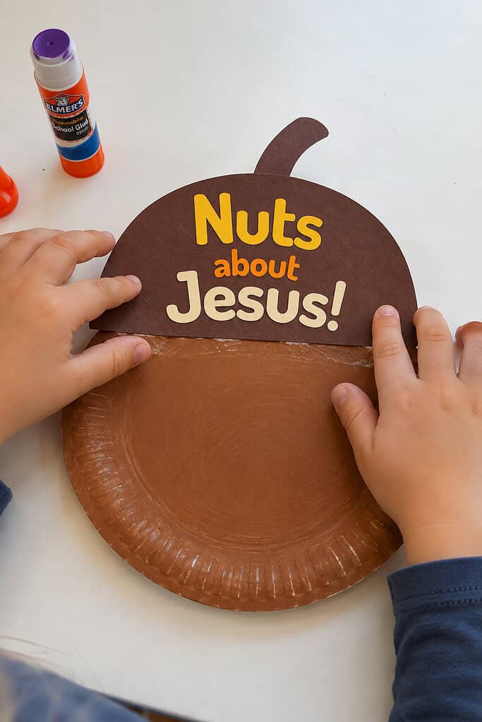 A child gluing the "Nuts about Jesus!" cap onto the brown paper plate for the Nuts About Jesus acorn paper plate craft