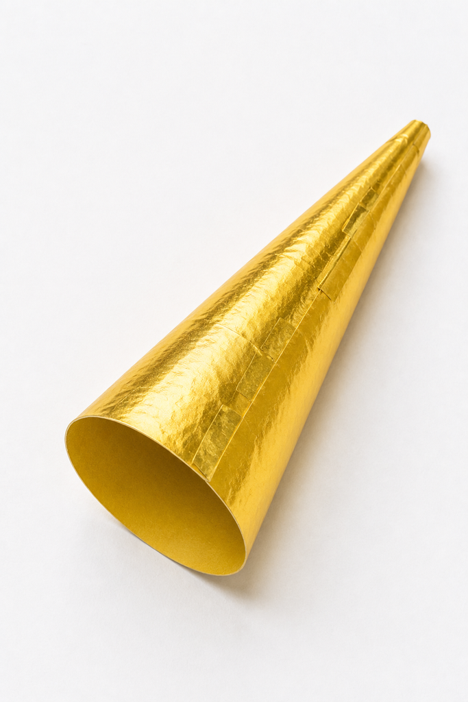 A paper cone trumpet craft wrapped in shiny gold paper, wide at one end and narrow at the other.