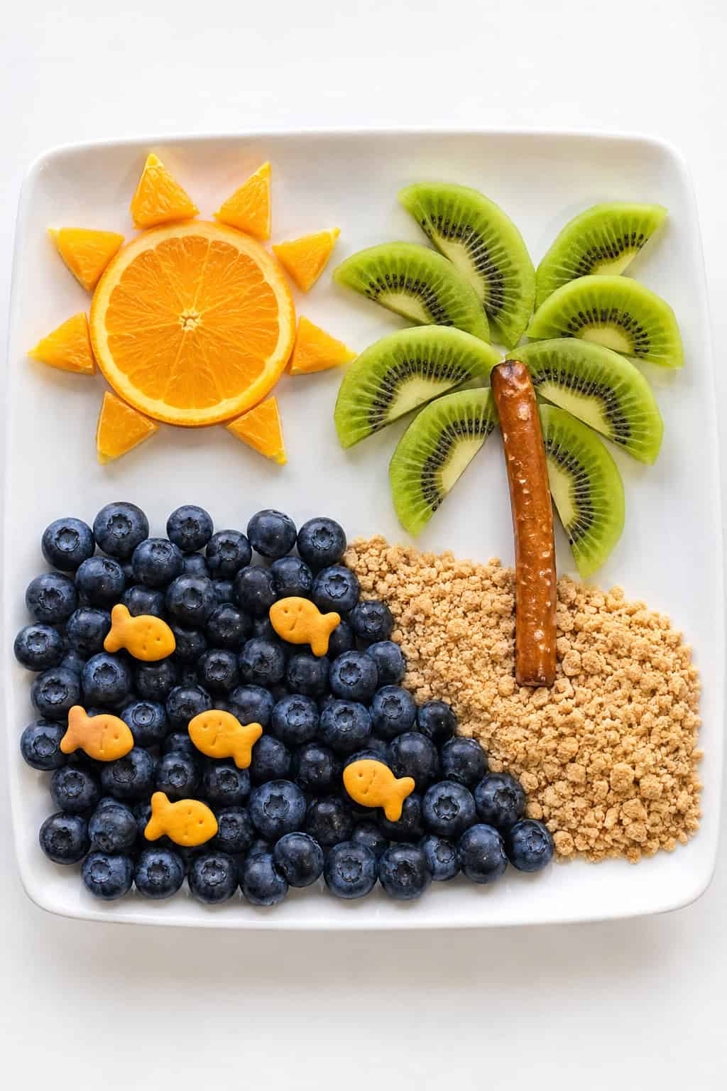 A Jonah and the whale snack plate with a kiwi palm tree, blueberry sea, and orange sun.