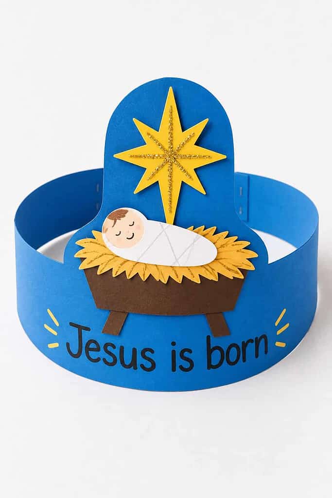 A paper headband with a manger, baby Jesus, a yellow star, and the words Jesus is born across the front.