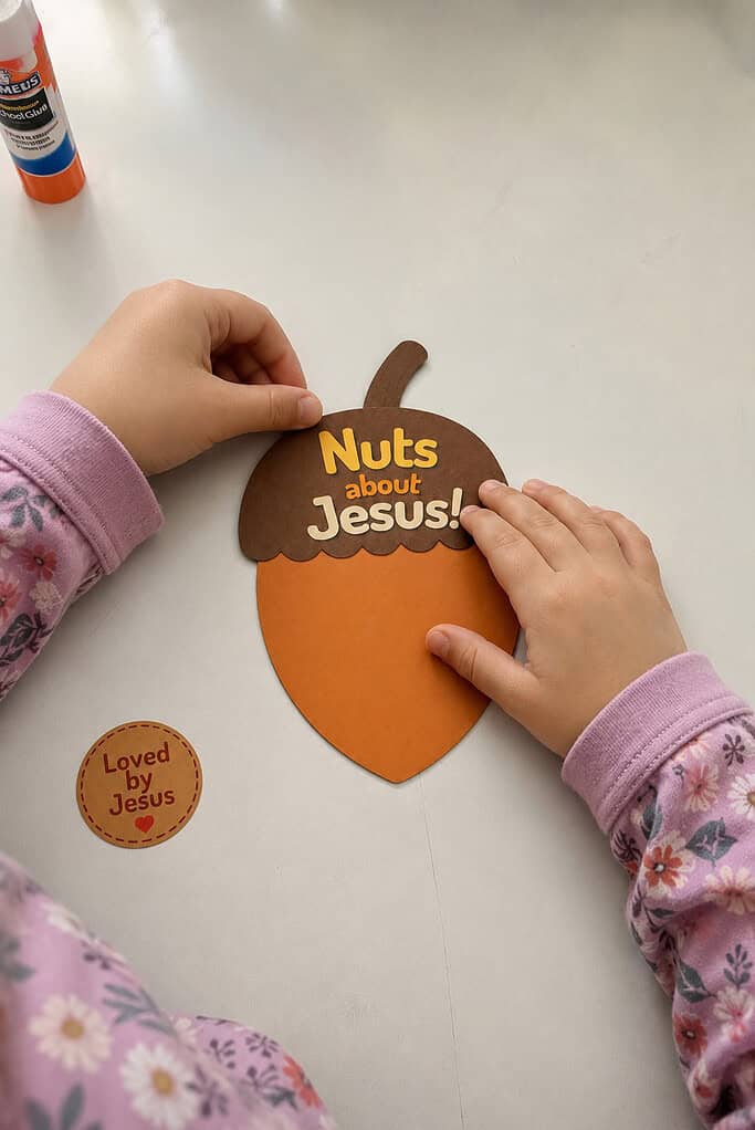 A child gluing the "Nuts about Jesus!" cap onto the acorn body for the Nuts About Jesus acorn craft