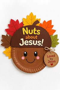 Finished Nuts About Jesus acorn paper plate craft with a smiling face, fall leaves, and a "Loved by Jesus" tag