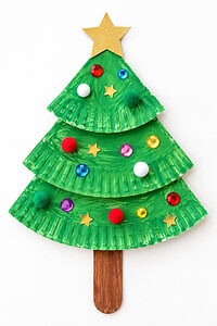 A paper plate Chistmas tree with white pom-poms and gold stars on a white table.