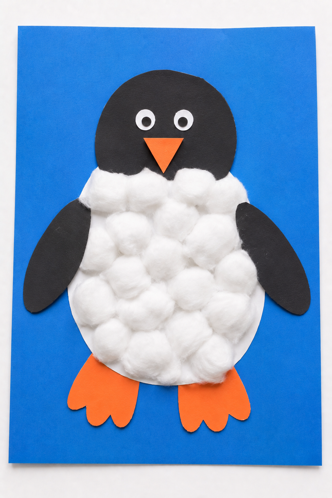 a penguin with a puffy cotton ball belly, black paper head and wings, and orange beak and feet on blue paper