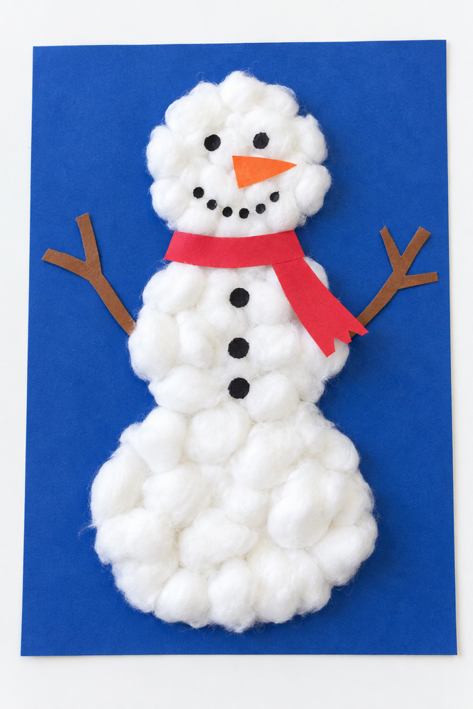 a cotton ball snowman craft on blue paper with a red scarf, dot eyes, an orange nose, black buttons, and twig arms on a white table