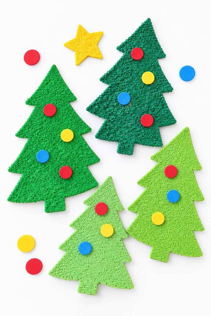 Four green craft-foam Christmas trees in different shades lay flat on a white surface.