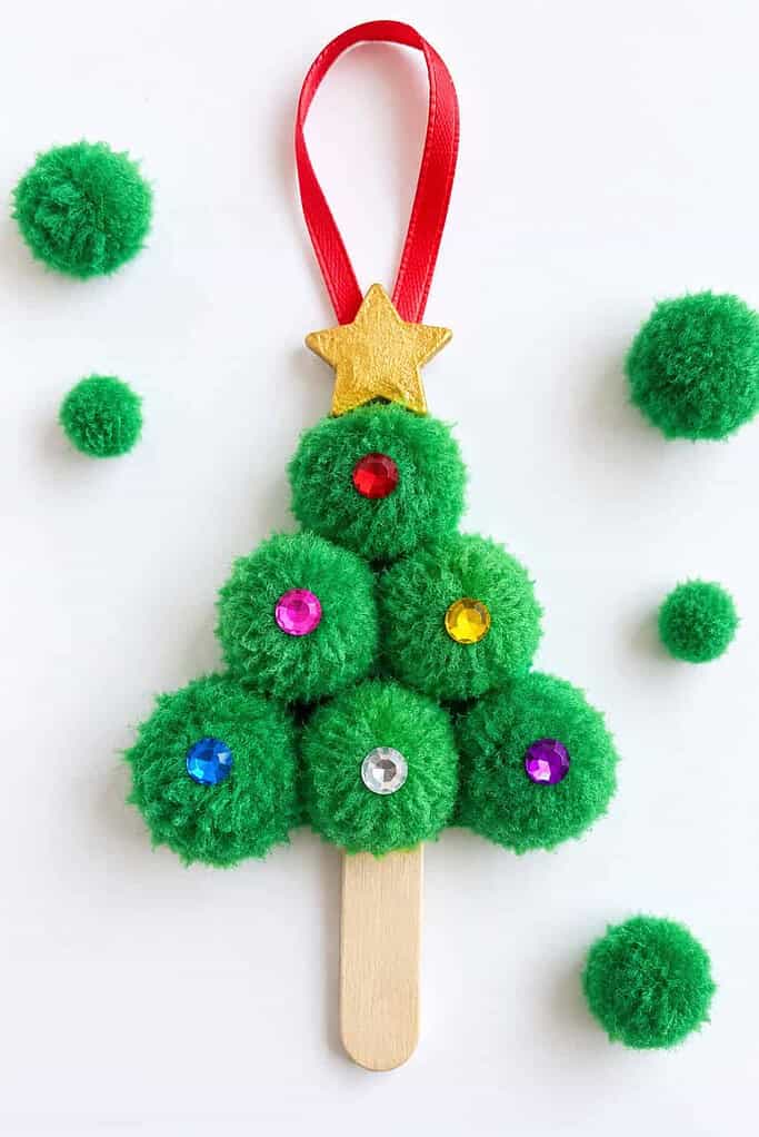 A Christmas tree made of green buttons on white card beside a jar of loose green buttons.