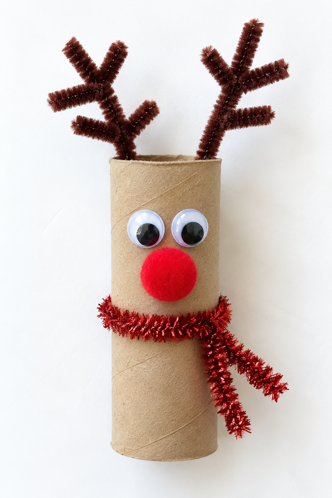 a cardboard tube reindeer with brown pipe cleaner antlers, googly eyes, a red pom-pom nose, and a red scarf on a white table