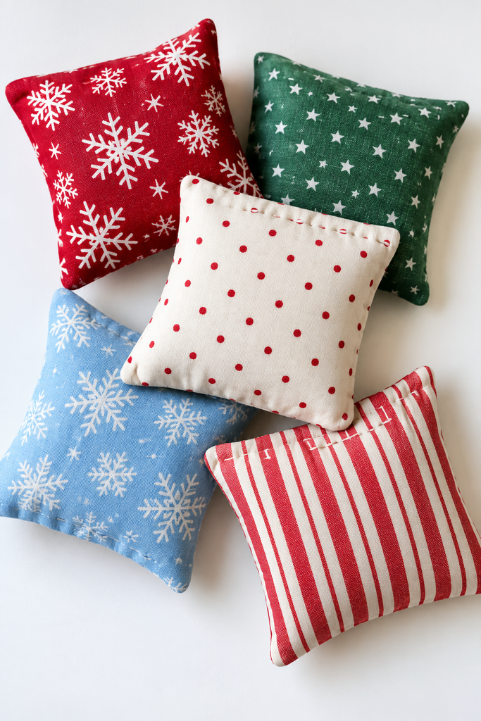 Small square rice-filled hand warmers in red, green, cream, blue, and striped Christmas fabrics