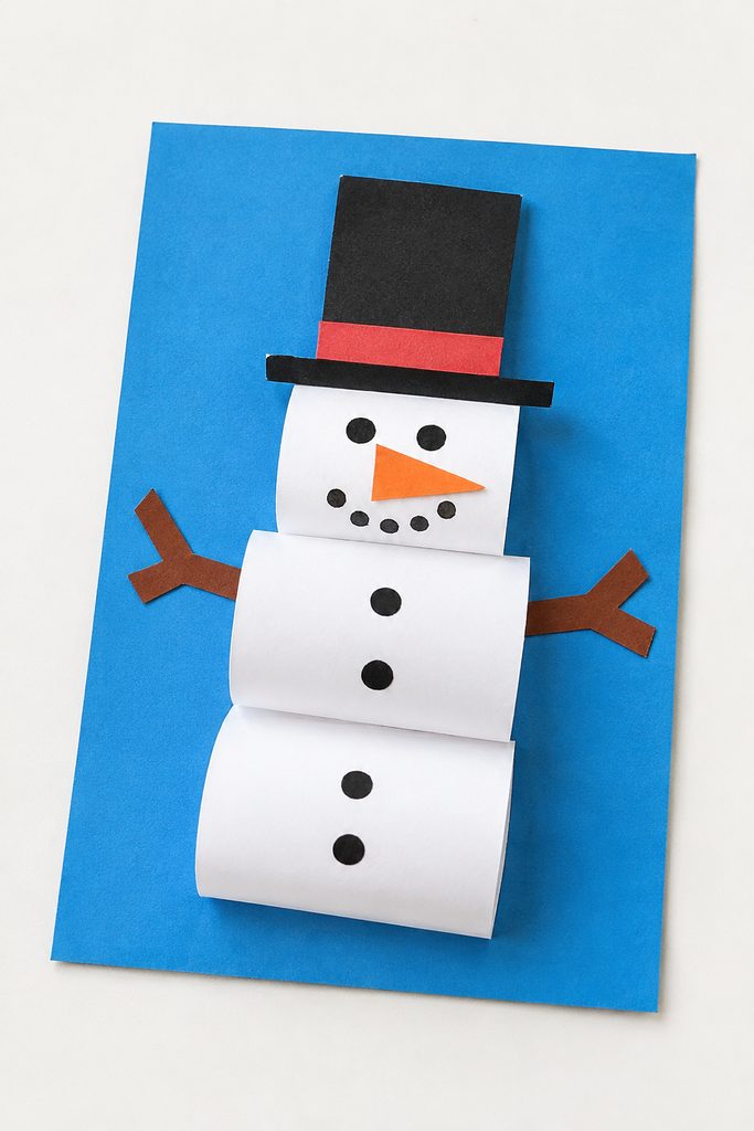 a 3D paper snowman craft made of rolled white paper loops on blue paper with a black hat, dot eyes, an orange nose, buttons, and paper arms on a white table