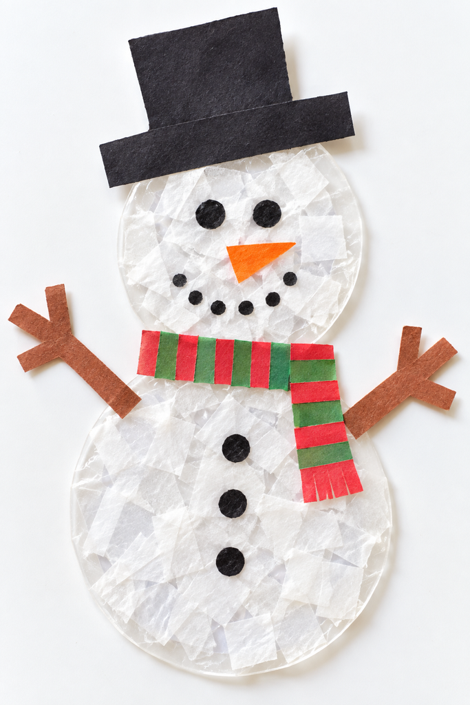 a tissue paper snowman suncatcher with a black hat, orange nose, dot eyes, and a scarf on a white table