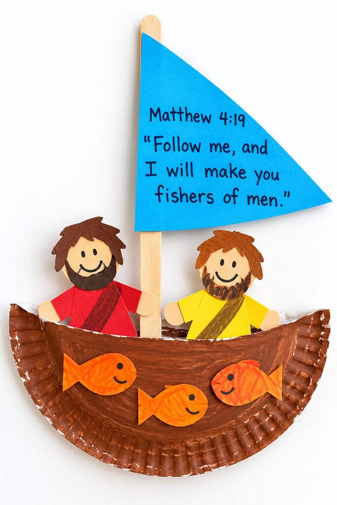 A kid-made paper plate fishing boat with a blue sail reading Matthew 4:19 Follow me and I will make you fishers of men, two paper disciples in red and yellow robes, and small orange paper fish in the boat.
