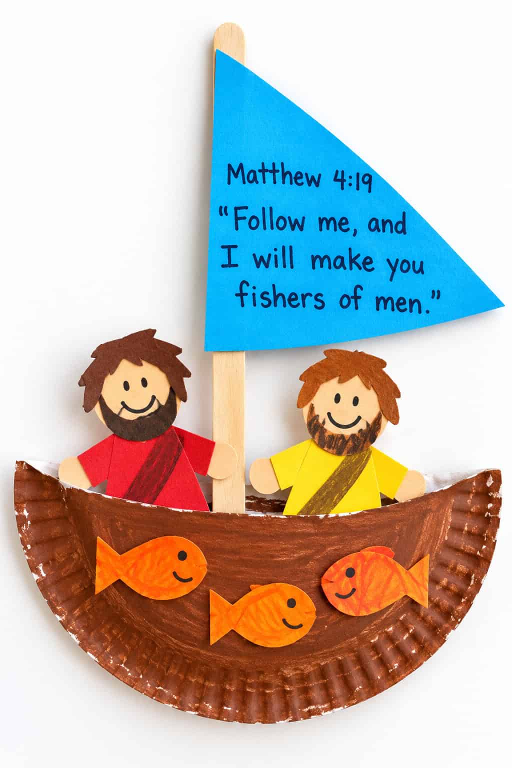 A kid-made paper plate fishing boat with a blue sail reading Matthew 4:19 Follow me and I will make you fishers of men, two paper disciples in red and yellow robes, and small orange paper fish in the boat.