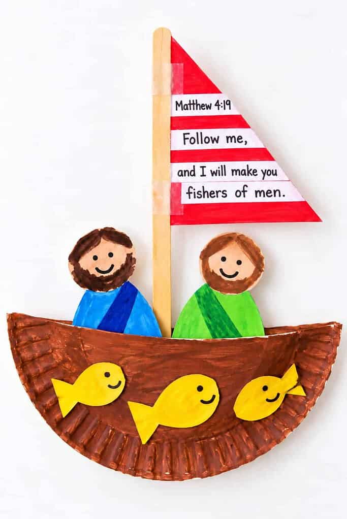 A folded brown paper plate boat with a red-and-white striped sail reading Matthew 4:19 Follow me and I will make you fishers of men, two paper disciples in blue and green robes, and little yellow paper fish in the boat.